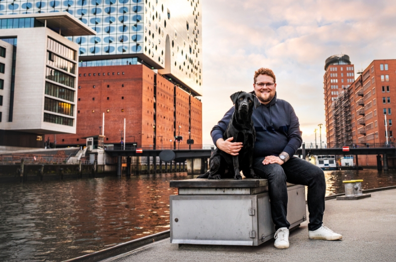 Foto von Steuerberater Philipp Feuer am Fluss sitzend, mit seiner Hündin Summer
